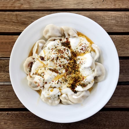 Manti dumplings in a white bowl on a wooden table
