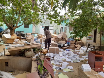 An African man searches through debris, papers and piles of cardboard boxes left in a courtyard by looters