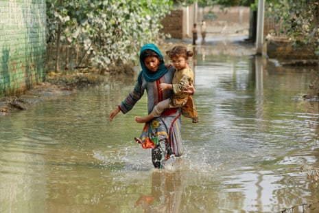 A girl carries her sibling as she walks through stranded flood water, following rains and floods during the monsoon season in Nowshera, Pakistan, last September.