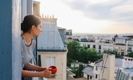 A woman leaning out the window of an apartment in Paris at sunrise