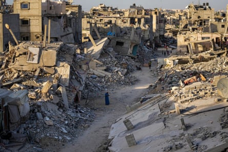 Palestinians walk through the destruction left by the Israeli air and ground offensive on Khan Younis, 12 September