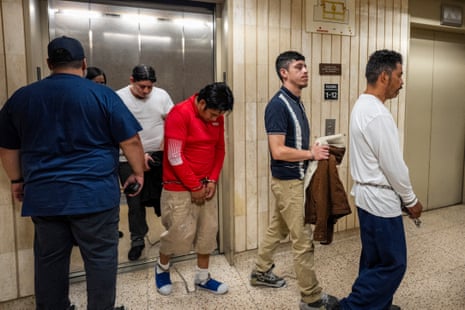 men with handcuffs and ankle shackles walk out of an elevator