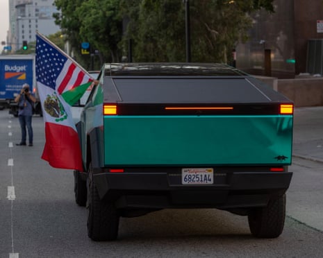 A half-Mexican and half-American flag waves from a Tesla Cybertruck.