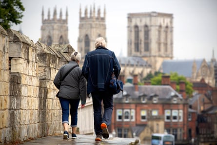 People walk along the Roman city walls towards York Minster and York town centre in North Yorkshire.