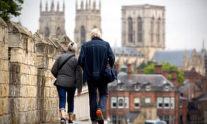 People walk along the Roman city walls towards York Minster and York town centre in North Yorkshire.