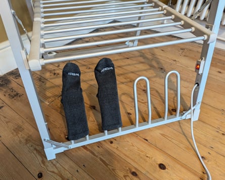 A pair of dark socks dries on the lower bar of a heated airer