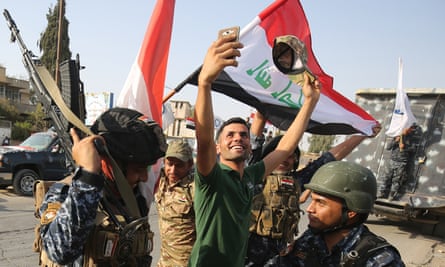 An Iraqi man takes a selfie with federal police officers as they celebrate the ‘liberation’ of Mosul from Islamic State.