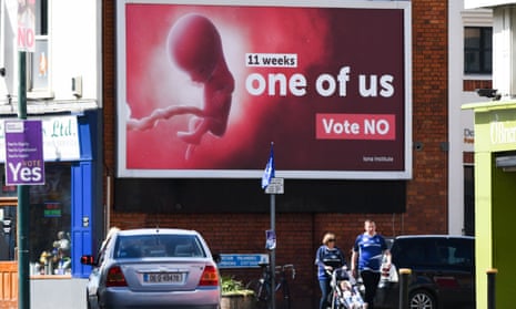 Pedestrians pass a billboard urging a no vote in the referendum to preserve the eighth amendment of the Irish constitution