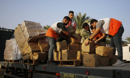 Men sort out boxes on the back of a truck under a blue sky