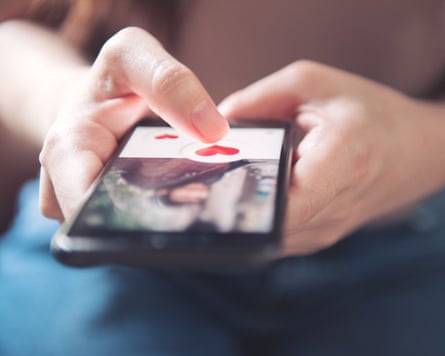 Finger of woman pushing a heart icon on a screen in smartphone dating app