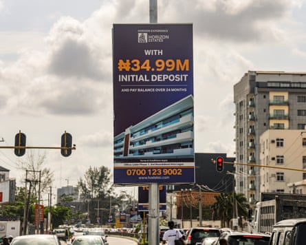An estate agent’s sign reads ‘with ₦34.99m initial deposit’ above an image of flats