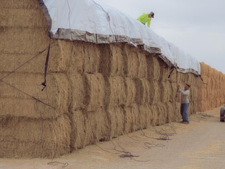 bundles of hay stacked on top of each other being covered by plastic