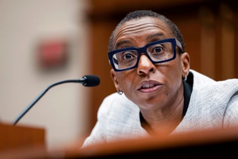 A Black woman with glasses speaks into a microphone.