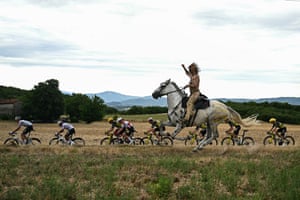 A man on horseback rides alongside the peloton.