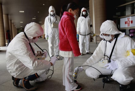 Workers in white hazmat suits scan a child