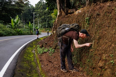 Alan Rockefeller examina a parede de terra da floresta tropical em busca de cogumelos em Pastaza, Equador.