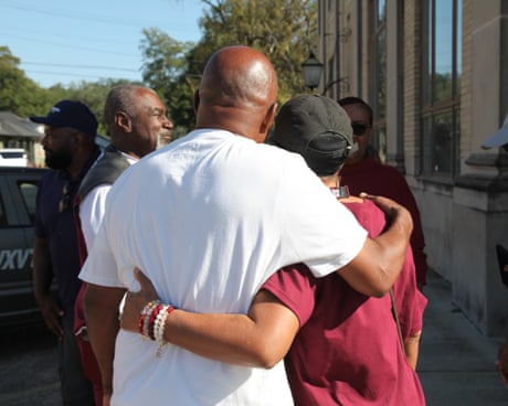 Man and woman embrace on a sidewalk.