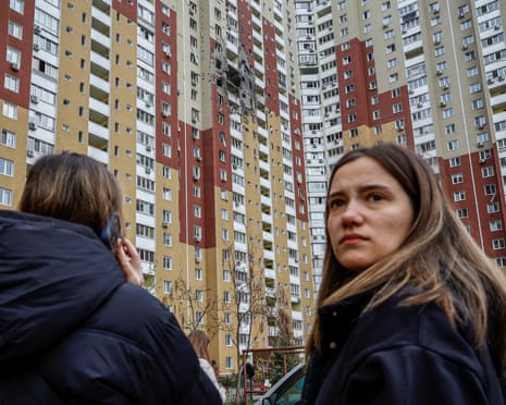 Residents stand near an apartment building damaged by Russian drone strikes in Kyiv