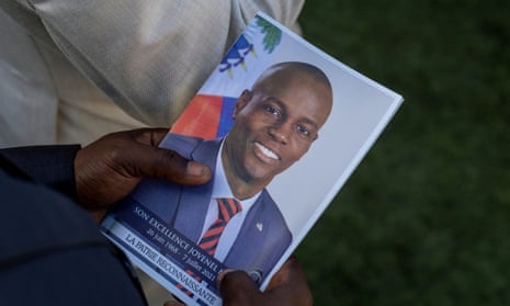 A person holds a photo of Jovenel Moïse during his funeral in Cap-Haiten, Haiti, in July 2021. 