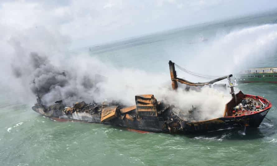 A cargo ship on fire and sinking as it lists to one side 