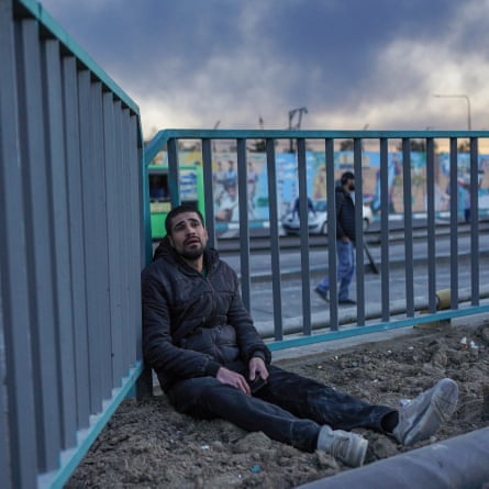 A young man looks emotional as she sits leaning against railings