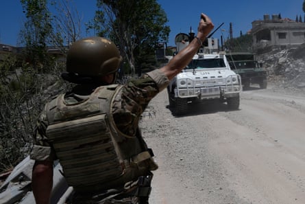 A Lebanese soldier with hand raised in the air as a white UN vehicle approaches