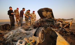 Iraqi security forces inspect the site of the bomb attack at a police checkpoint on a highway near Nasiriyah.