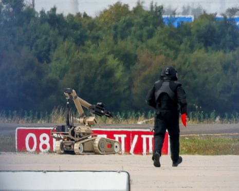 A police officer in protective clothing walks next to an explosive-disarming robot at Leipzig airport in Schkeuditz, Germany, 5 August, 2026.