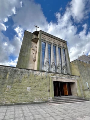 A church built from exposed concrete in a block design and with carved concrete figure detailing