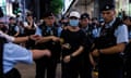 A member of the public is led away by police on a crowded street in Hong Kong