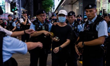 A man wearing a face mask is led away by police on a crowded street in Hong Kong