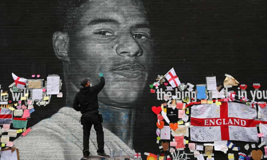 An artist repairs the defaced Manchester mural of Marcus Rashford, one of the England players who received a torrent of racist abuse online after the team’s Euro 2020 loss to Italy.