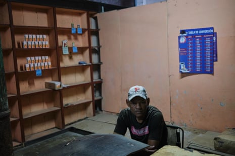 A man sits at a table in a room with mostly empty shelves