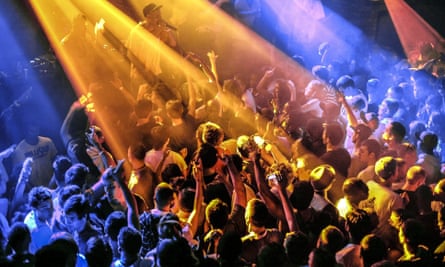 A packed dancefloor in a nightclub illuminated by blue and orange lights