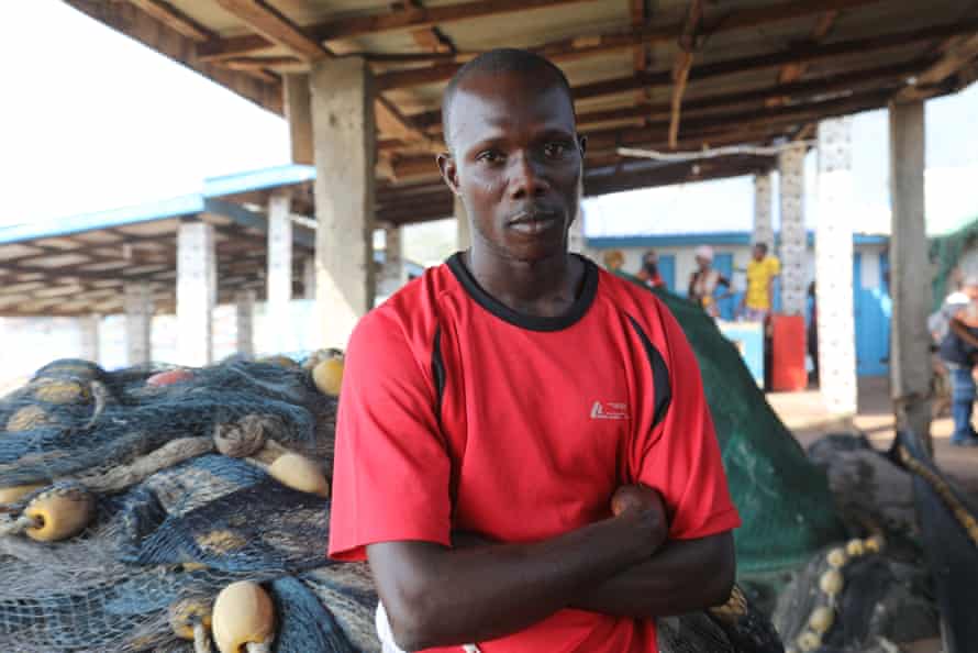 A fisherman sitting amid nets on a fishing boat