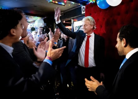 Geert Wilders waves to a room of people who are applauding him