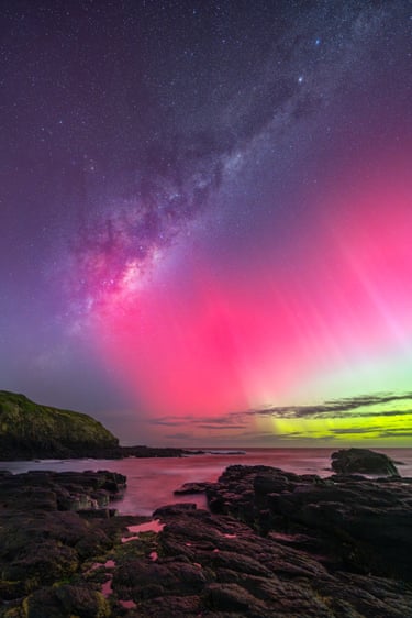 Bright pink and green aurora over beach