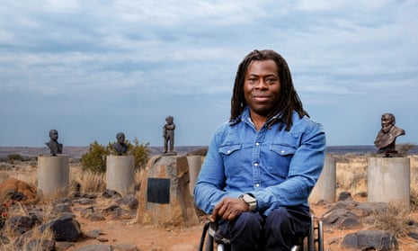 Ade Adepitan in front of a collection of busts of Afrikaner leaders and symbols in Orania, South Africa