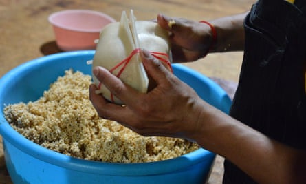 A worker packs amaranth from a blue bowl into a plastic skull mold.