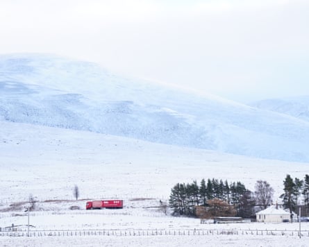 A lone lorry travels along a road surrounded by snow-covered fields and hills