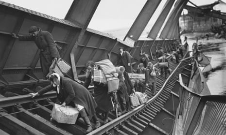 Refugees fleeing to safety behind allied lines cross a damaged railway bridge over the river Elbe in Germany on 1 May 1945.