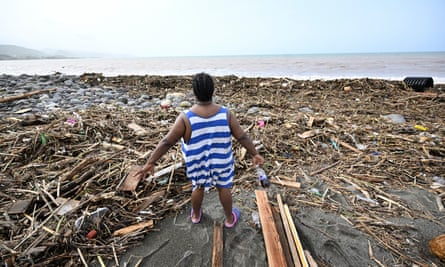 A woman looks at a beach covered in debris
