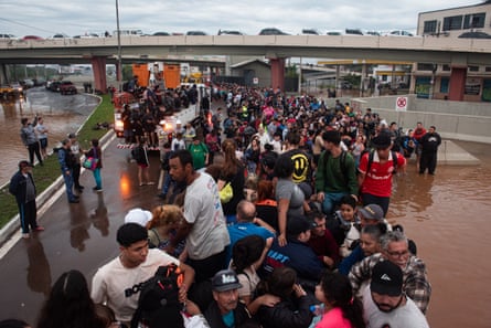 People on a raised roadway in Porto Alegre in May 2024 to escape the flood waters, seen below them.