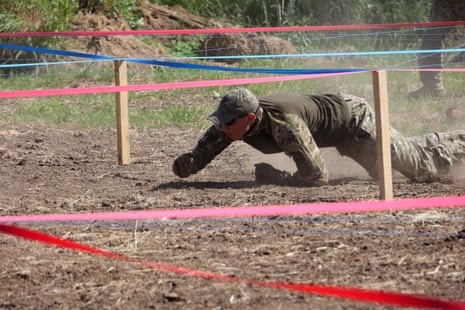 A member of Ukrainian service personnel crawls through an obstacle course during a training session.