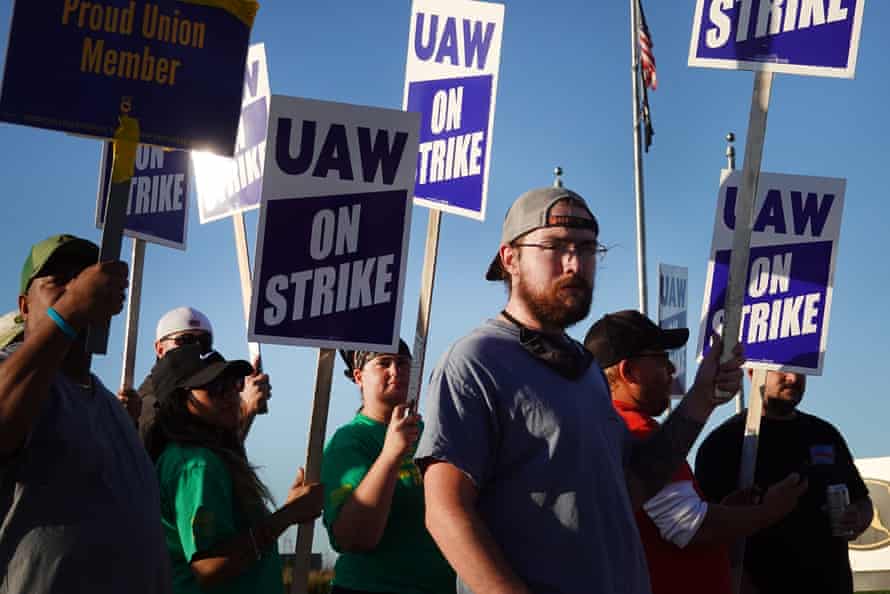 People hold signs saying 'UAW on strike'