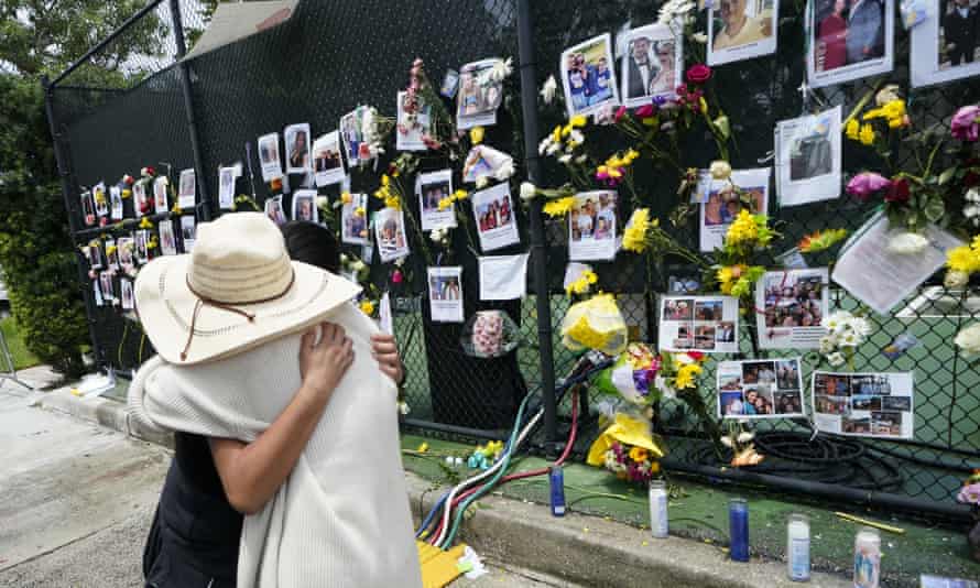 People embrace at a make-shift memorial outside St Joseph Catholic church in Surfside.