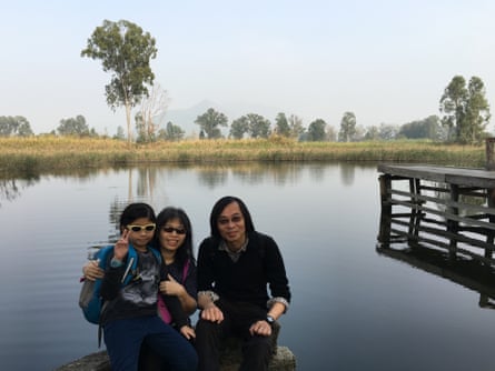 The family sititng next to a body of water, looking at the camera
