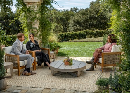 Prince Harry and Meghan, Duchess of Sussex, being interviewed on a patio by Oprah Winfrey