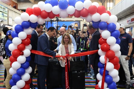 Passengers smiling as a red ribbon is cut in an archway of red, white and blue balloons