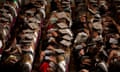 Rows of students wearing gowns and mortarboards clap during a graduation ceremony